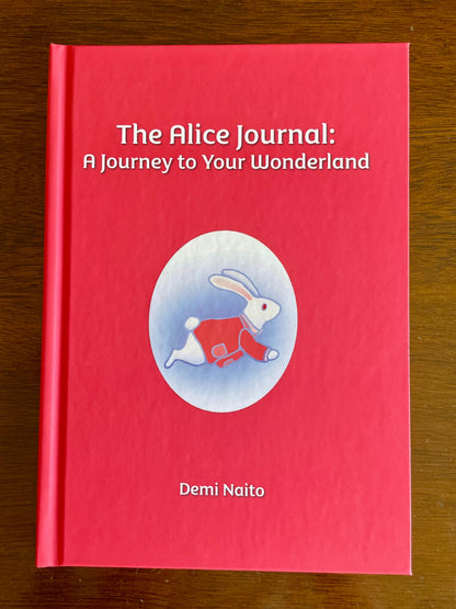 The hardcover version of  'The Alice Journal: A Journey to Your Wonderland' by Demi Naito on a wooden surface