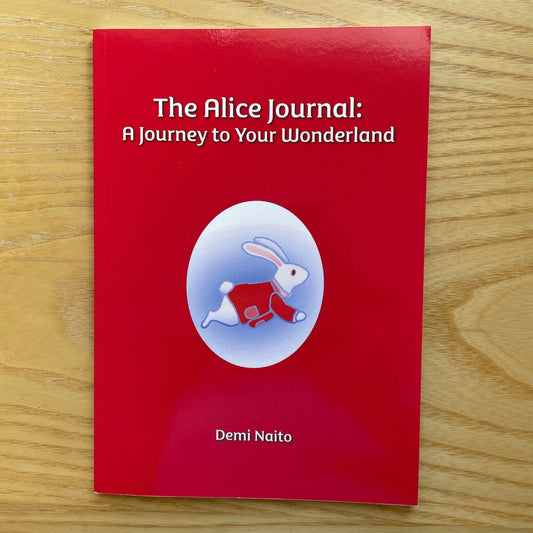 The Alice Journal: A Journey to Your Wonderland by Demi Natio, featuring a red cover with a white rabbit illustration, placed on a light wood grain surface.