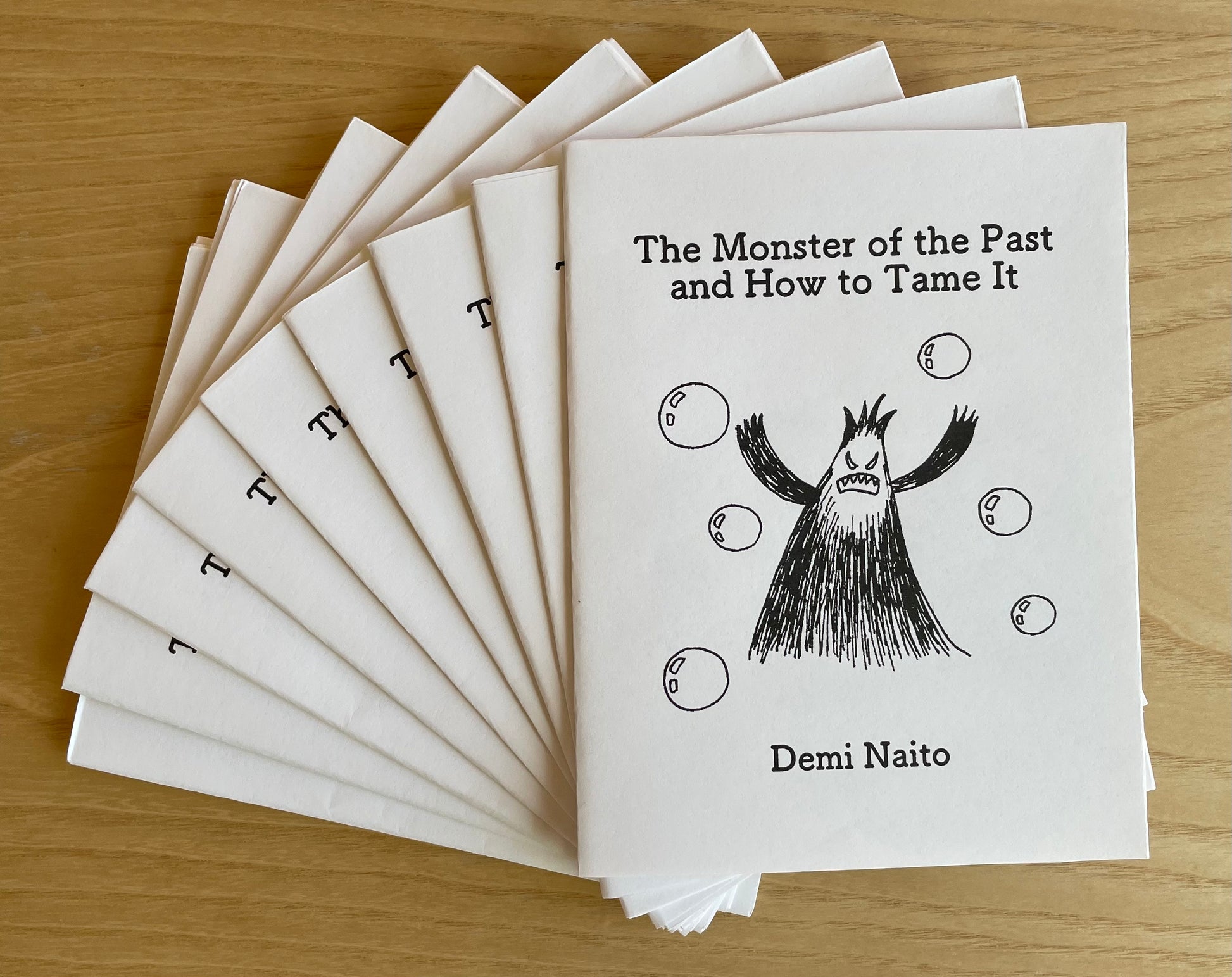 Stack of zines titled 'The Monster of the Past and How to Tame It' by Demi Naito.